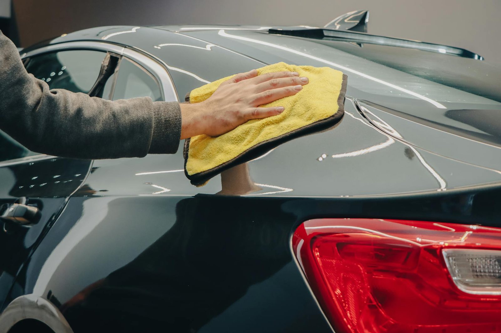 hand wiping a car with a cloth