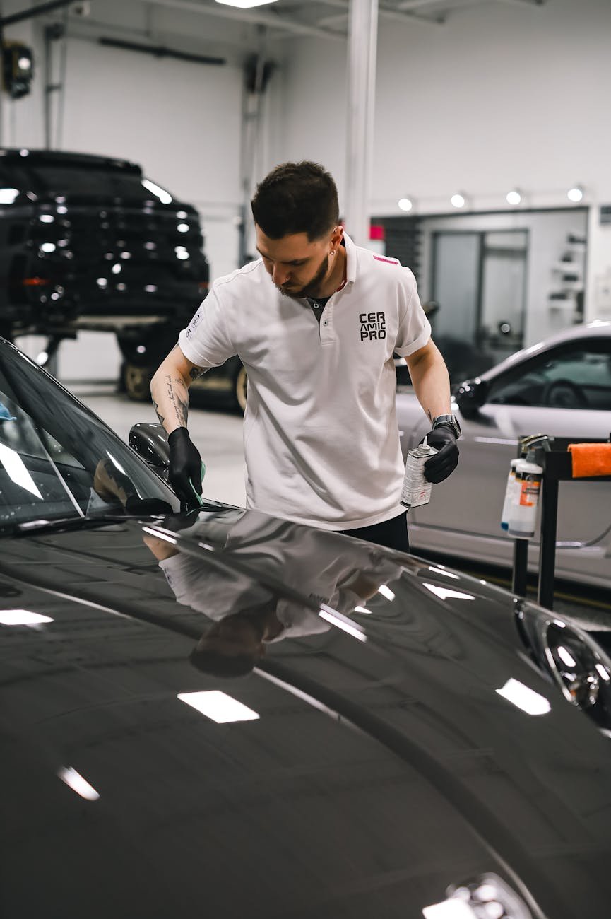 employee cleaning shiny hood of car