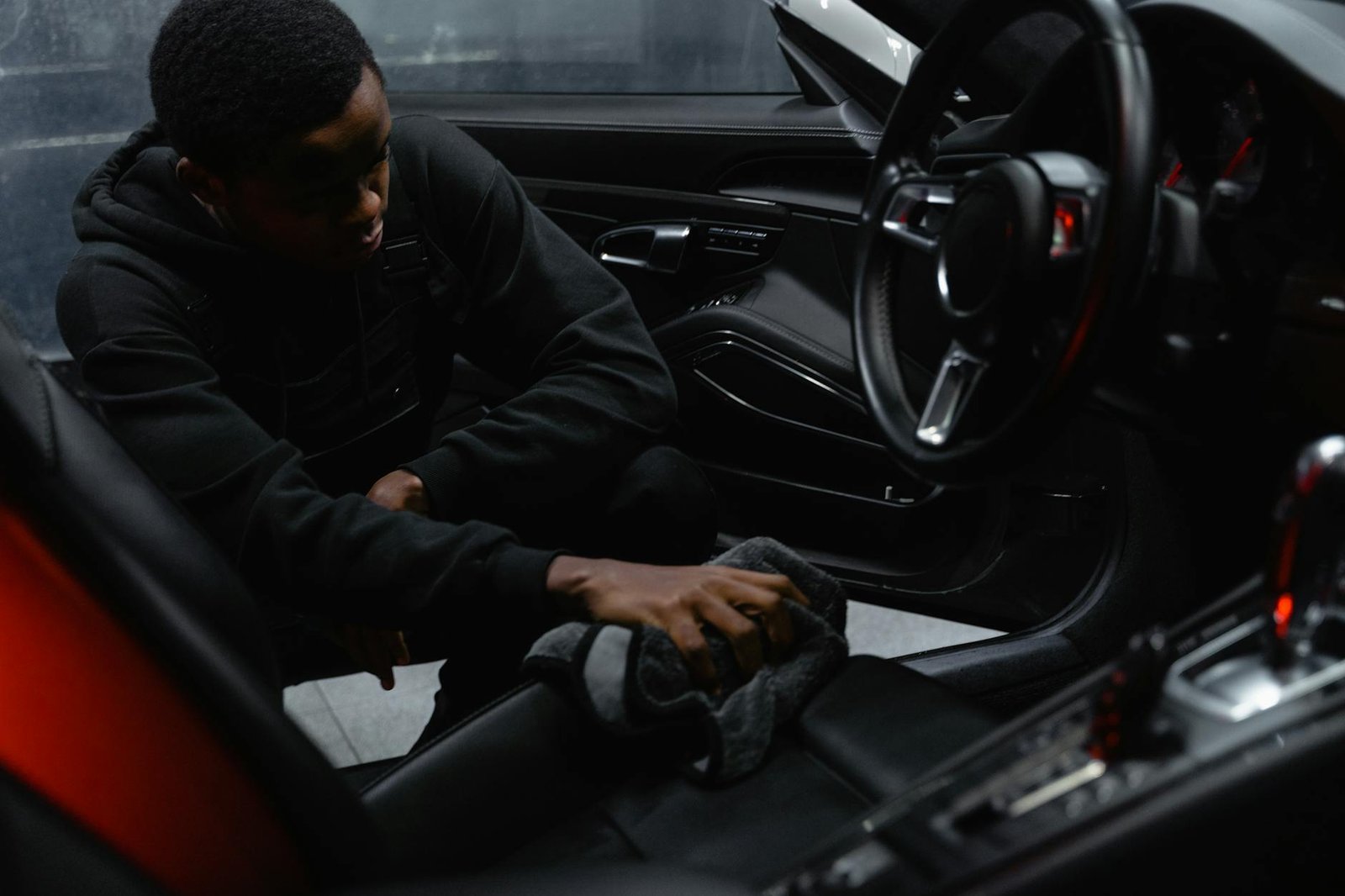 a man in black jacket cleaning the seat of a car