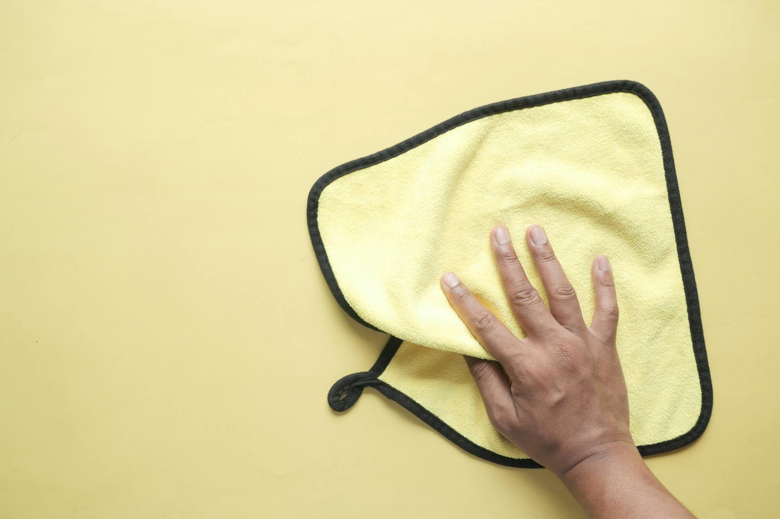 hand holding a yellow microfiber towel